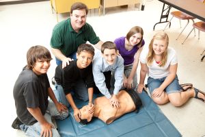 Symbolbild: Gruppe aus Jugendlichen lernt an einer Puppe die Herzdruckmassage