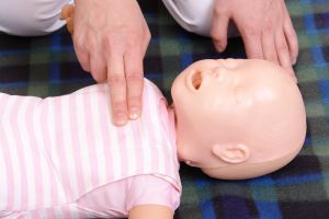 Symbolbild: Herzdruckmassage mit zwei Fingern an einer Baby Schulungs-Puppe